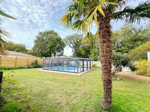 a palm tree in a yard with a glass house at Villa-des-eaux Claires in Puymoyen