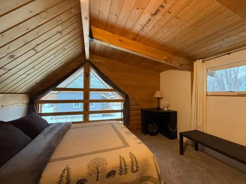 a bed in a room with a large window at Talkeetna Log Cabin with Hot Tub Unit 1 in Talkeetna
