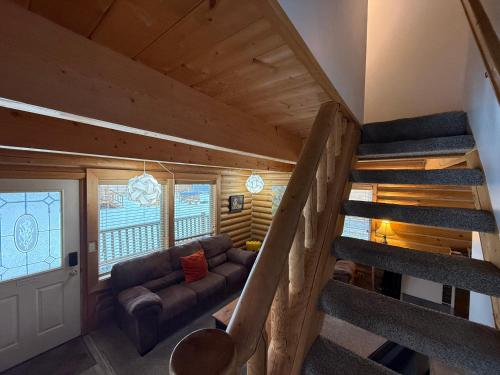 a living room with a couch and stairs in a tiny house at Talkeetna Log Cabin with Hot Tub Unit 1 in Talkeetna