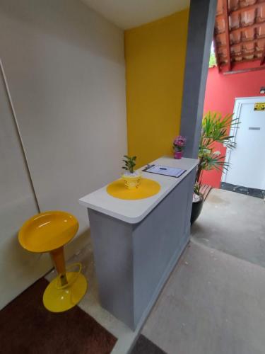 a bathroom with a yellow sink and a stool at Pousada Ideal Guarujá - Estúdios Mobiliados, Ar-Condicionado e Cozinha in Guarujá