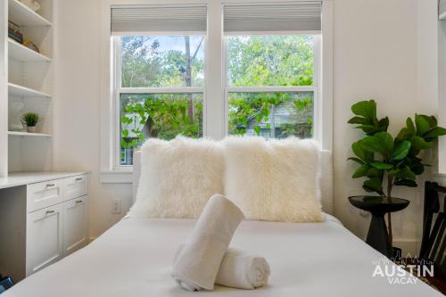 ein weißes Bett mit weißen Kissen und einem Fenster in der Unterkunft Pet Friendly East Cesar Chavez Home Near Downtown in Austin