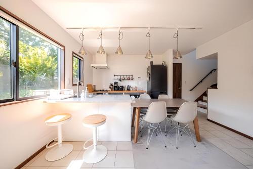 a kitchen with a table and stools in a room at 屋根付き屋外ガス式BBQ ぐらんぱる公園シャボテン動物公園絶好立地貸別荘stella 星空眺望 遊具 ホームシアター 大画面任天堂スイッチ in Ito