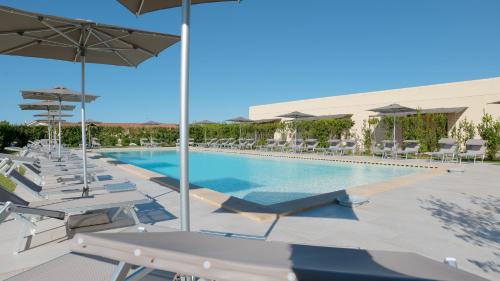 a swimming pool with lounge chairs and umbrellas at Delle Rose, Hotel & Horse Riding in Torre Vado