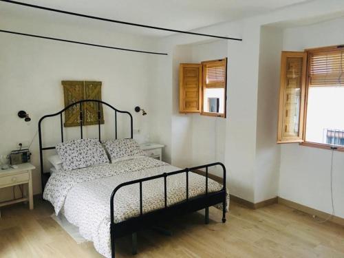 a bedroom with a bed and two windows at La Casita Tipica in Zuheros