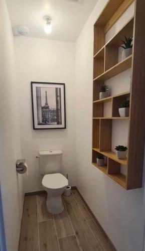 a bathroom with a toilet and a picture on the wall at Charmante maison raffinée, conviviale & familiale in Virandeville