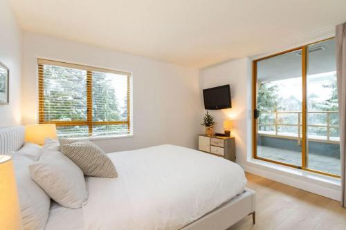 a white bedroom with a large bed and a window at Renovated 2Bed-2Bath in Village with Pool, Hot Tub, and Sauna in Whistler