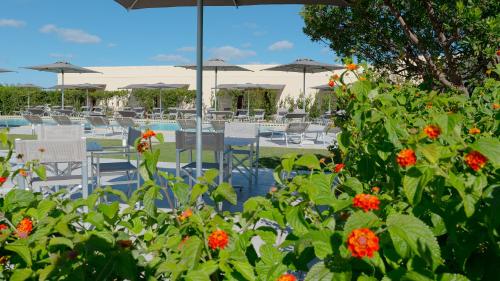 a group of tables and chairs with flowers and umbrellas at Delle Rose, Hotel & Horse Riding in Torre Vado