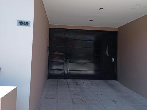 a black garage door in a room with a tile floor at Lugar Encantado Con Estacionamiento Gratuito 2 in Olavarría