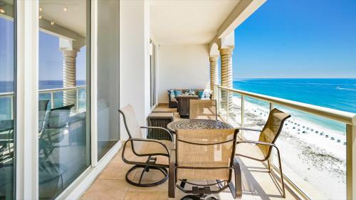 a balcony with a table and chairs and the ocean at Beach Club Gulf Front 3B Condo - 1604 in Pensacola Beach