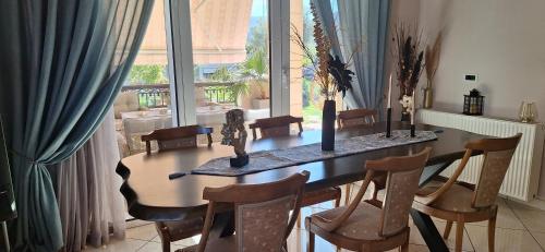 a dining room table with chairs and a large window at Modern Villa in Chania in Perivólia