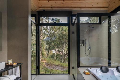 a bathroom with a shower and a tub with a window at Vale Sagrado in Urubici