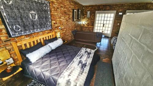 a bedroom with a bed and a brick wall at 2K City Studios Not Self catering in Graskop