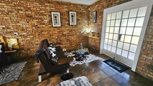 a living room with a chair and a brick wall at 2K City Studios Not Self catering in Graskop