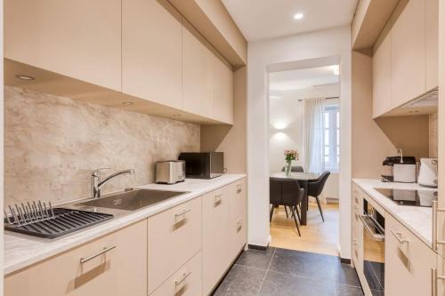 - une cuisine avec des placards blancs, un évier et une table dans l'établissement Cosy Duplex in the heart of Beaupassage, à Paris