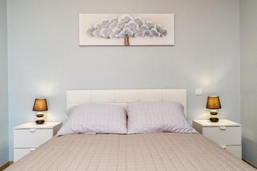 a bedroom with a white bed with two lamps on tables at Goncalves House - AC and private parking in Calheta