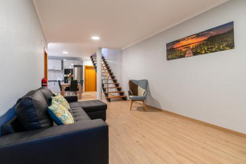 a living room with a couch and a stair case at Goncalves House - AC and private parking in Calheta
