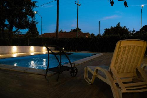 two chairs sitting next to a swimming pool at night at Le Pernici Apartments in Mascalucia