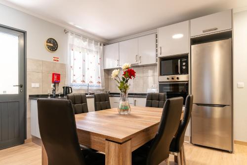 a kitchen and dining room with a wooden table and chairs at Goncalves House - AC and private parking in Calheta