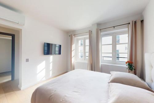 une chambre blanche avec un lit et deux fenêtres dans l'établissement A pearl of Paris, à Paris