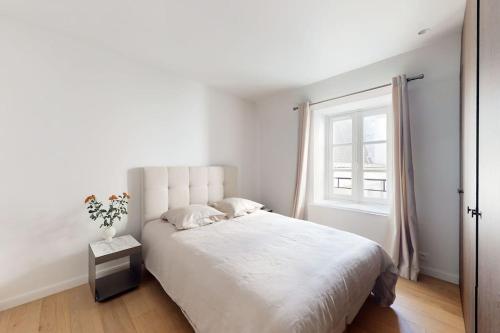 une chambre blanche avec un grand lit et une fenêtre dans l'établissement A pearl of Paris, à Paris