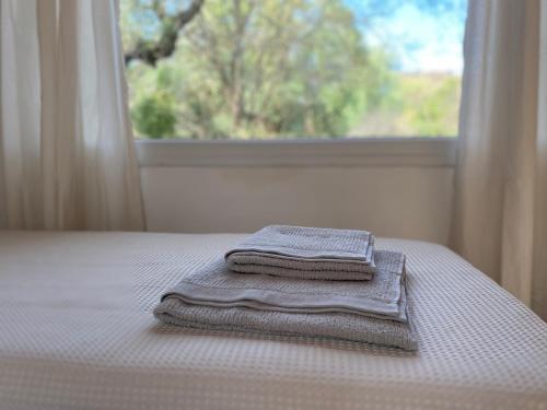 a stack of towels sitting on a bed in front of a window at Casa Natu- Naturaleza in San Marcos Sierras