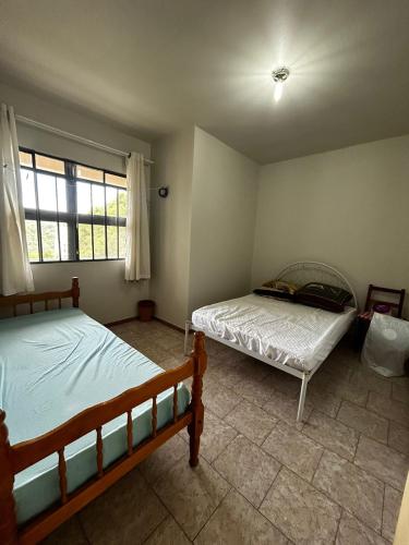 a bedroom with two beds and a window at Casa ampla de 4 quartos in Piratuba