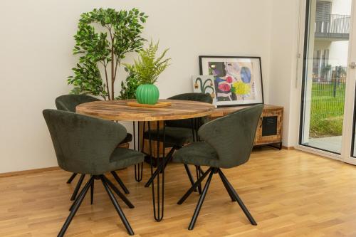 a dining room table with chairs and a green vase on it at Eggenberg City Suites - Self Check-In in Graz