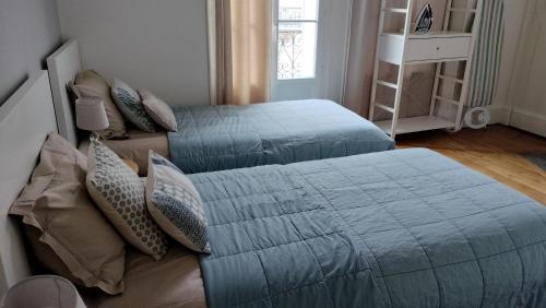 - une chambre avec 2 lits dotés de couvertures et d'oreillers bleus dans l'établissement Appartement F3 au balcon de la Place du Martroi, à Orléans
