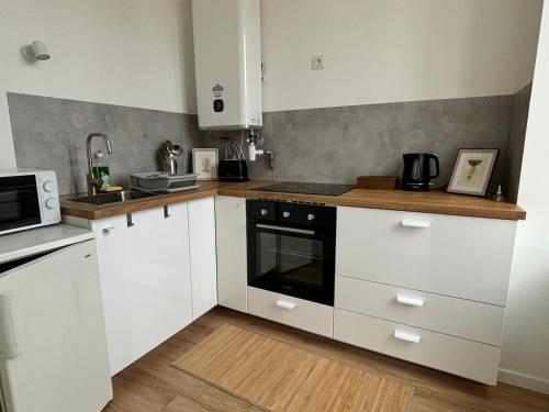 une cuisine avec des armoires blanches et un micro-ondes dans l'établissement Appartement au coeur de la ville, à La Ferté-Bernard
