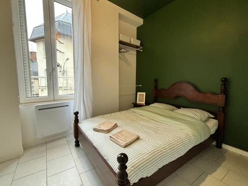 una camera da letto con un letto con pareti verdi e una finestra di Appartement au coeur de la ville a La Ferté-Bernard