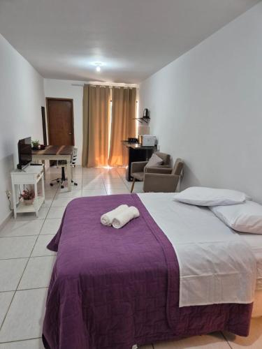 a bedroom with a large bed with a purple blanket at Estúdio Charmoso no Centro de Apiaí in Apiaí
