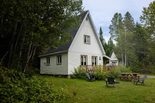 a white house with a table and chairs in the yard at Gîte du Mont-Albert - Sepaq in Sainte-Anne-des-Monts