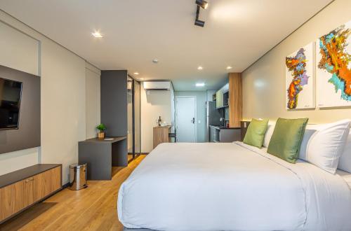 um quarto com uma grande cama branca com travesseiros verdes em Next Paulista by Viva - Apartamentos completos ao lado da Av Paulista e MASP em São Paulo