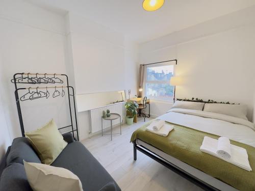 a bedroom with a large bed and a couch at Leyton House - SleepyLodge in London