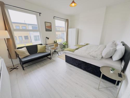 a bedroom with a bed and a couch and a chair at Leyton House - SleepyLodge in London