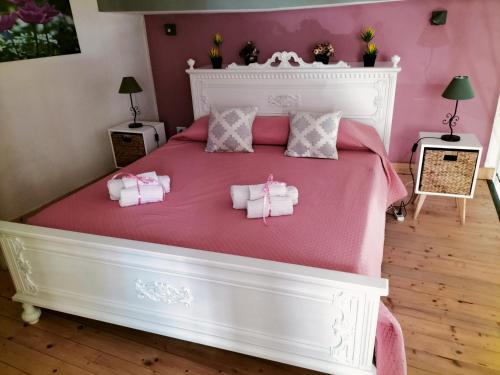 a bedroom with a large white bed with pink sheets at La casa di Anita nel cuore di Segesta in Calatafimi