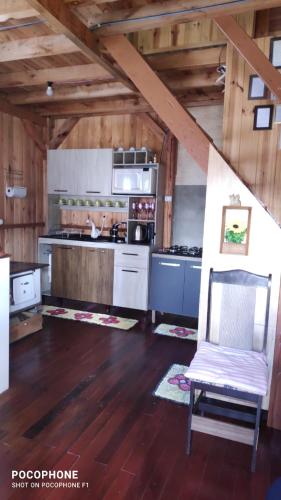 a kitchen with wooden floors and a chair in a room at Chalé 2 pinheiros in Urubici