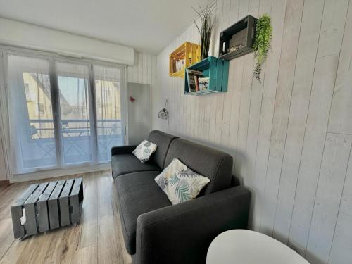 a living room with a couch and a table at Le petit Courseulles - entre le port et la mer in Courseulles-sur-Mer