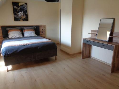 a bedroom with a bed and a desk with a mirror at Maison avec terrain clos in Denneville-Plage