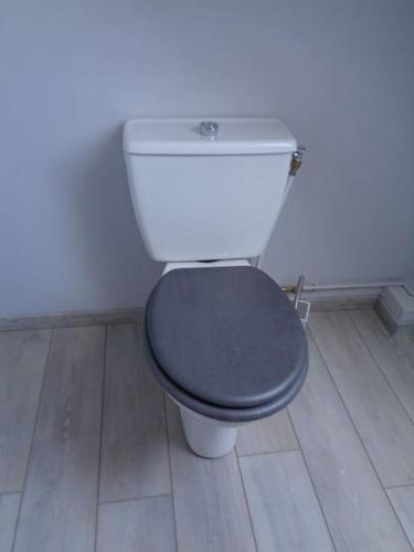 a white toilet with a black seat in a bathroom at Maison avec terrain clos in Denneville-Plage