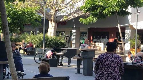 a group of people sitting on benches in a park at A cozy room economy class in the central thriving area next to Shiba & Bar Ilan in Ramat Gan