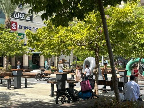 a group of people sitting on benches in a park at A cozy room economy class in the central thriving area next to Shiba & Bar Ilan in Ramat Gan