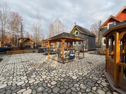 a stone patio with a pavilion in a yard at Talkeetna Log Cabin with Hot Tub Unit 1 in Talkeetna