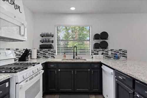 a kitchen with black cabinets and a sink and a window at Super Comfy Home with Hot Tub! in Round Rock