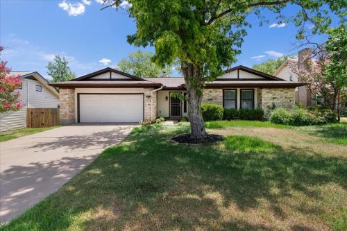 a house with a tree in front of a driveway at Super Comfy Home with Hot Tub! in Round Rock