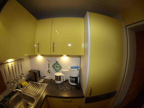 a small kitchen with yellow cabinets and a sink at FEWO Allgäu Chalet mit Schwimmbad und Sauna in Oberstdorf