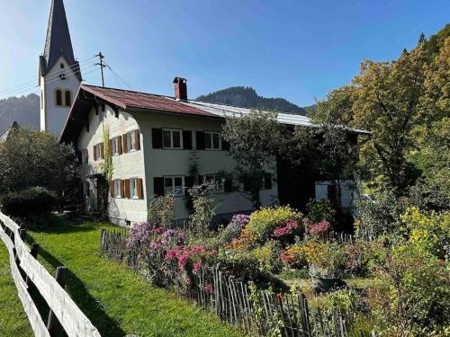 a church with a fence and flowers in front of it at FEWO Allgäu Chalet mit Schwimmbad und Sauna in Oberstdorf