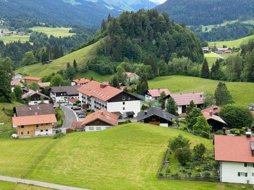 a small village on a green hill with houses at FEWO Allgäu Chalet mit Schwimmbad und Sauna in Oberstdorf