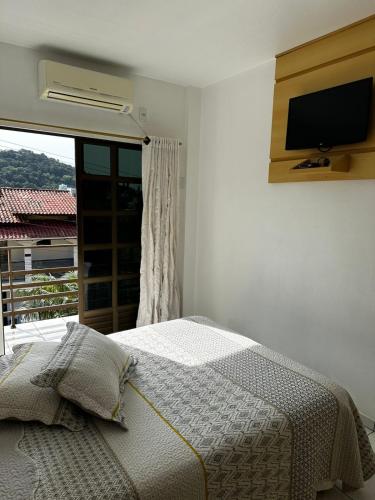 a bedroom with a bed and a television on the wall at Residencial Vista Bela in Bombinhas