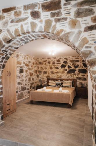 a bedroom with a bed in a stone wall at Lefteris Rooms in Kámbos